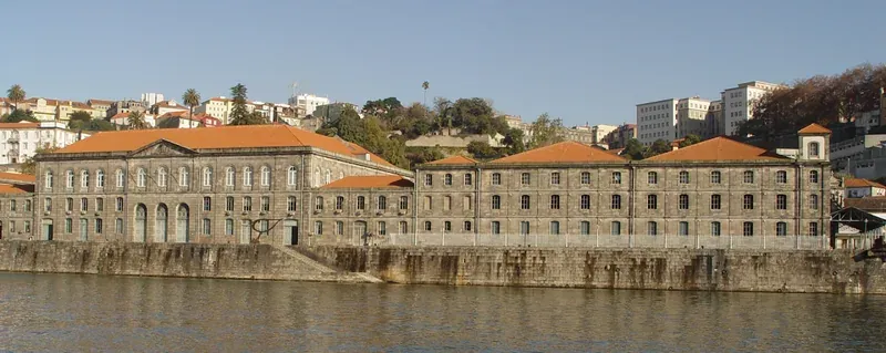 A long stone building with a tiled roof on the riverbank