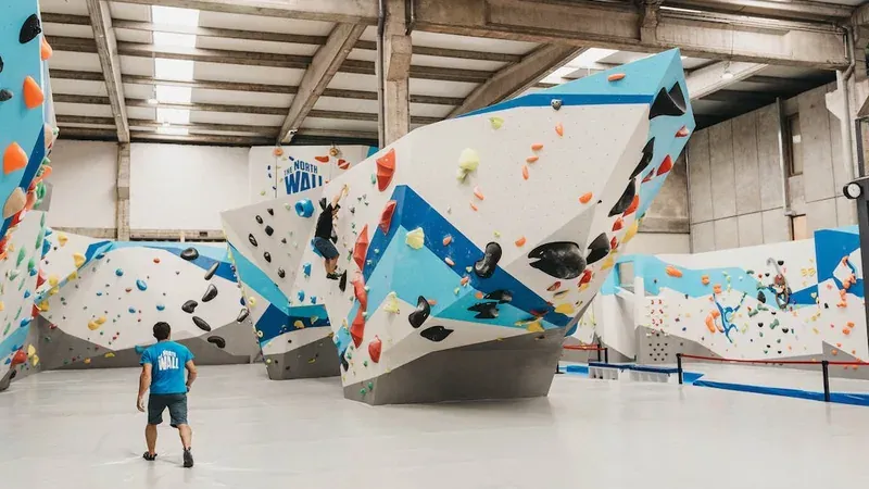 A climber looking up at the colourful holds of an indoor bouldering wall