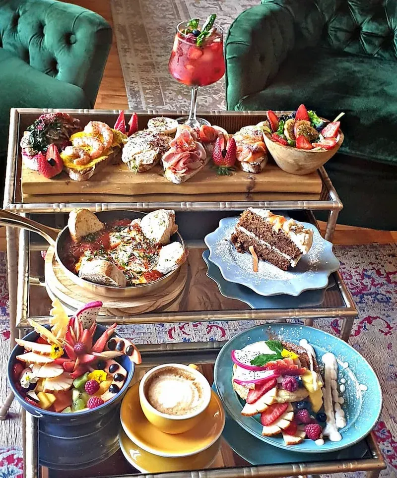 A tiered stand of brunch food with pastries, fruit, cake and a coffee