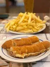 Cachorrinhos, thin toasted hot-dog sandwiches cut into pieces, with a plate of chips