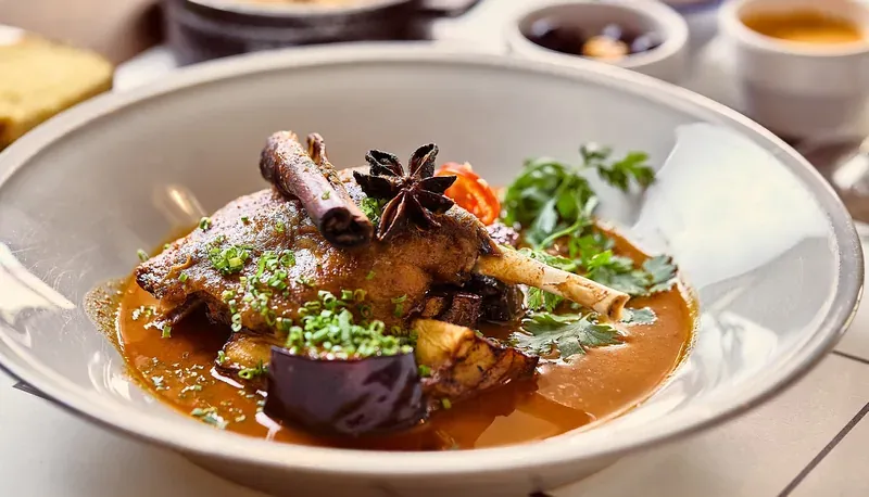 A bowl of braised meat in sauce, garnished with star anise and herbs