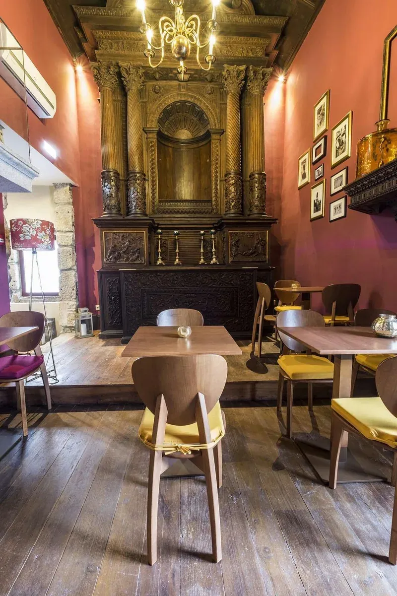 Inside the chapel wine bar: a carved altar behind café tables and chairs