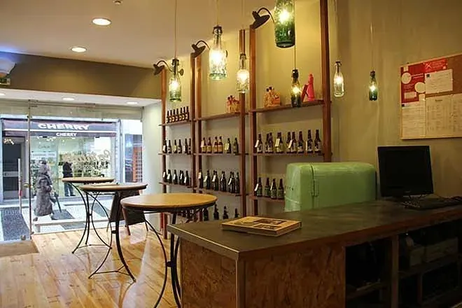Inside a craft beer shop, with bottles on the shelves and small high tables