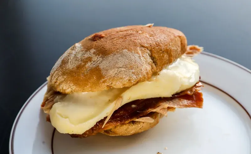 A crusty sandwich filled with sliced roast pork and melted Serra cheese