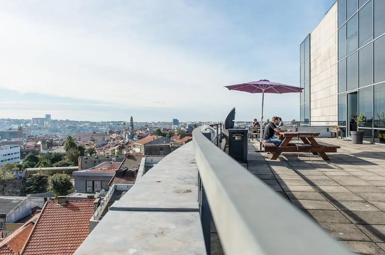 A rooftop terrace with a parasol and picnic tables, looking out over the rooftops of Porto