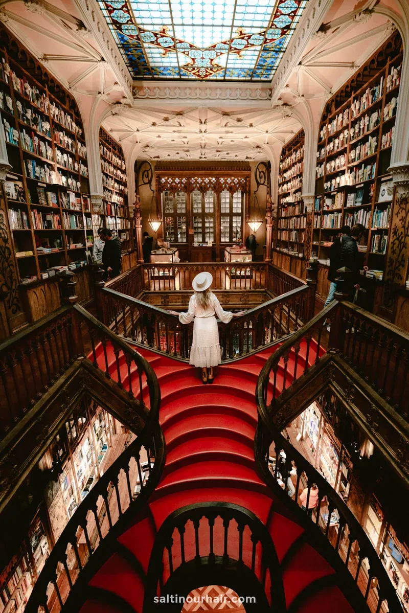 The red forked staircase inside Livraria Lello, surrounded by carved wooden bookshelves