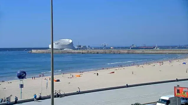 A wide sandy beach with a port terminal in the distance