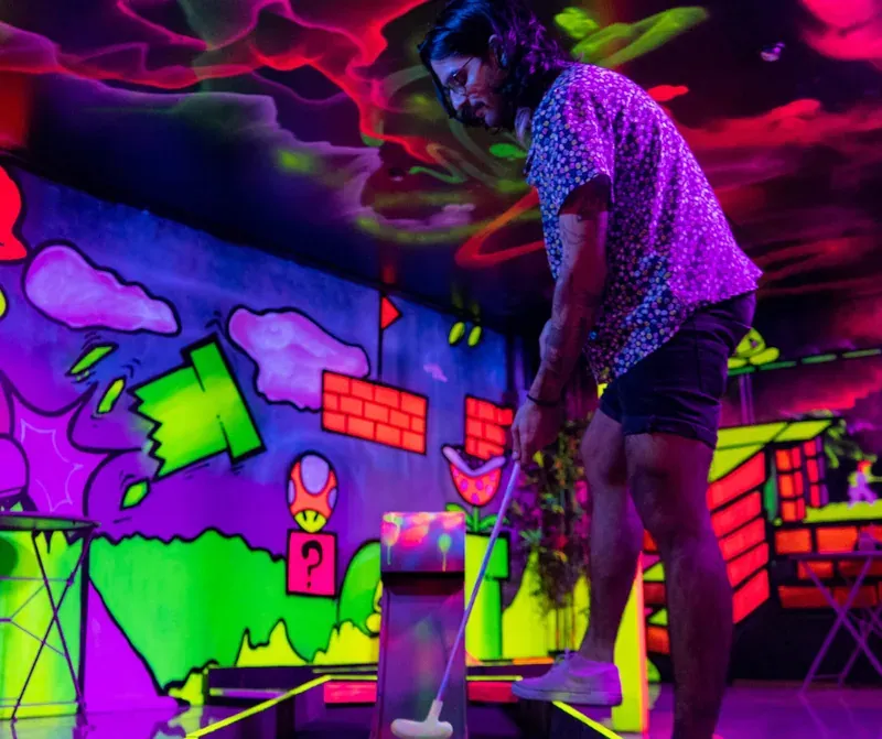 A man putting on a glow-in-the-dark mini golf course