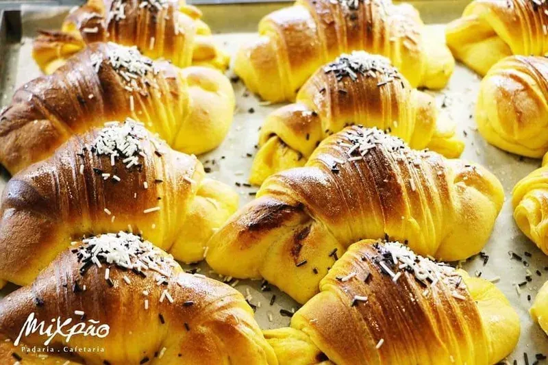 A tray of golden croissants sprinkled with chocolate
