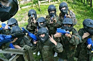 A group of paintball players in masks and camouflage holding markers