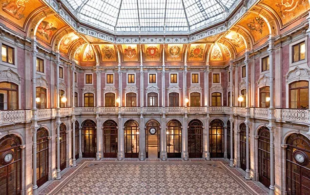 An arcaded interior courtyard under a glass dome inside Palácio da Bolsa