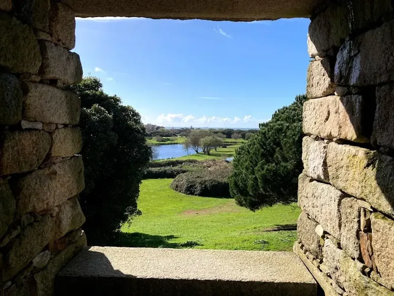 A green park and a lake seen through a stone window