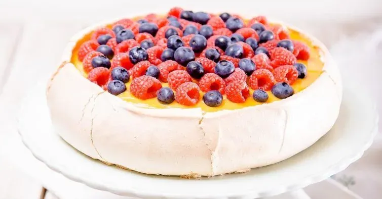 A pavlova topped with raspberries and blueberries