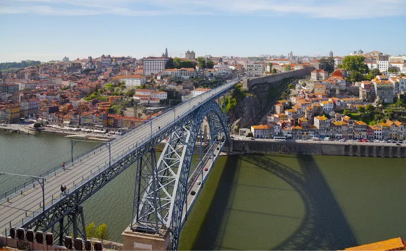 An iron arch bridge spanning the Douro, with Porto’s old town on the hill behind