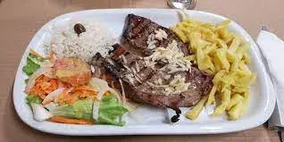 A grilled beef steak with chips, rice and salad on a white plate