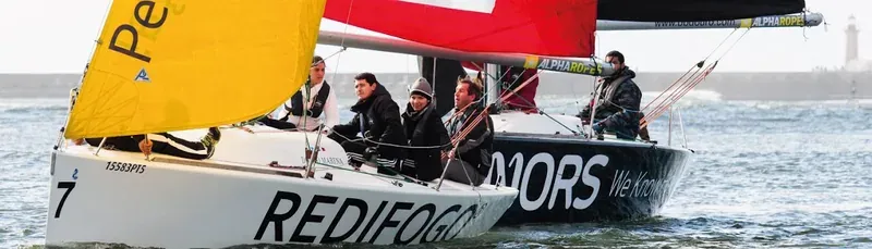 A team sailing a racing yacht with red and yellow sails