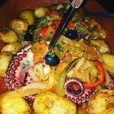 Roast octopus with potatoes, peppers, onion and olives