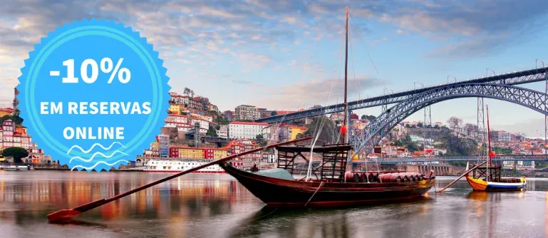 A traditional wooden boat on the Douro in front of the riverside and a bridge