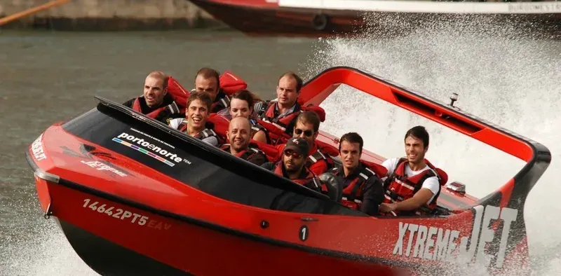 A group in life jackets on a red speedboat throwing up spray