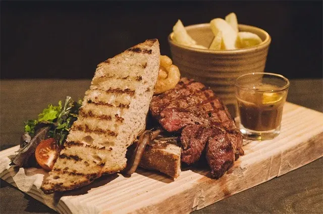 Grilled steak and toasted bread on a wooden board