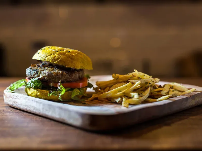 A vegan burger on a wooden board with chips
