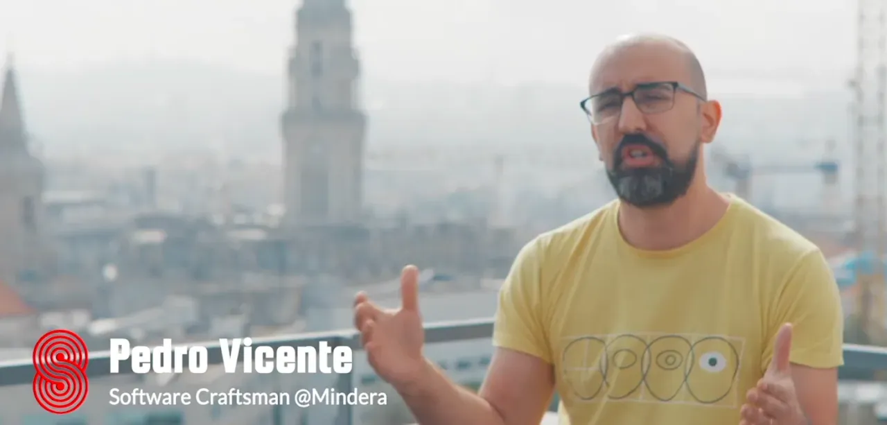 Documentary still: Pedro Vicente, captioned “Software Craftsman @Mindera”, talking on a rooftop above a hazy city