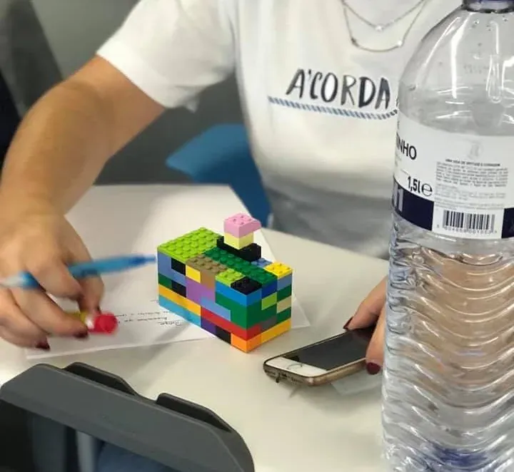 A participant’s hands beside a small, multicoloured LEGO build on a sheet of notes